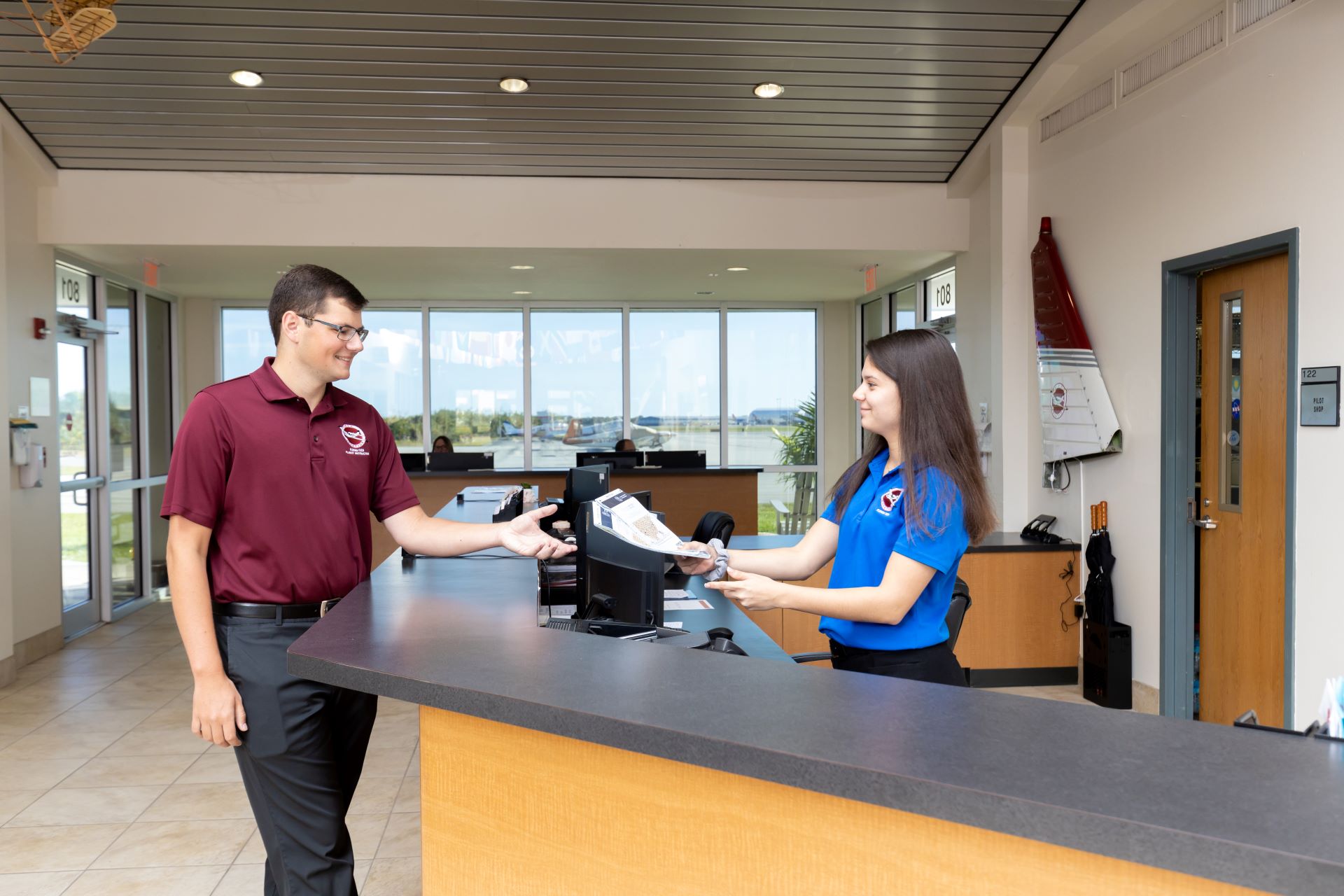 A student receiving a flyer from a university receptionist